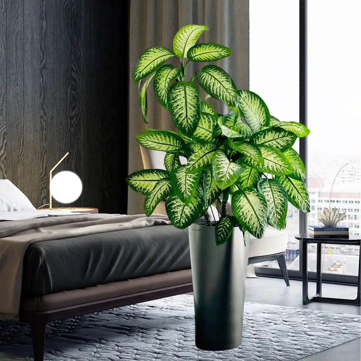 Modern bedroom interior featuring a large potted Dieffenbachia plant, an elegant bed, a stylish round bedside lamp, and a city view through the window, highlighting the best plants for bedroom decor.